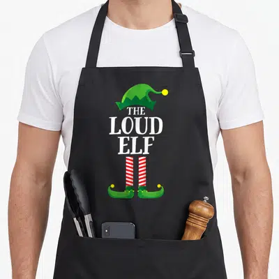 Loud elf apron - THE LOUD ELF text forms elf body with green hat and striped legs — shown on a black cotton canvas apron against a white background