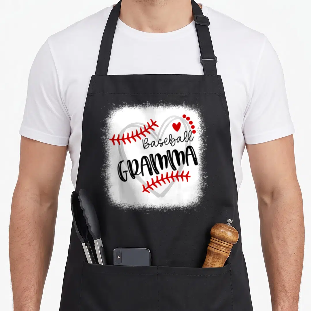 Gramma baseball apron - Grey heart outline with red stitches and black Baseball Gramma text — shown on a black cotton canvas apron against a white background