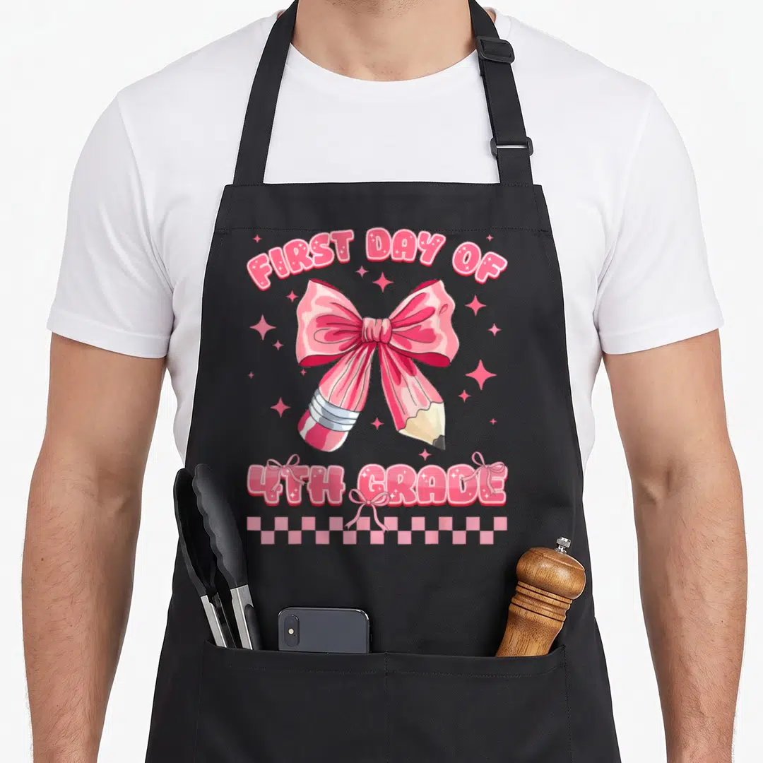 4th coquette apron - Pink pencil bow design with first day of 4th grade text and checkerboard border — shown on a black cotton canvas apron against a white background