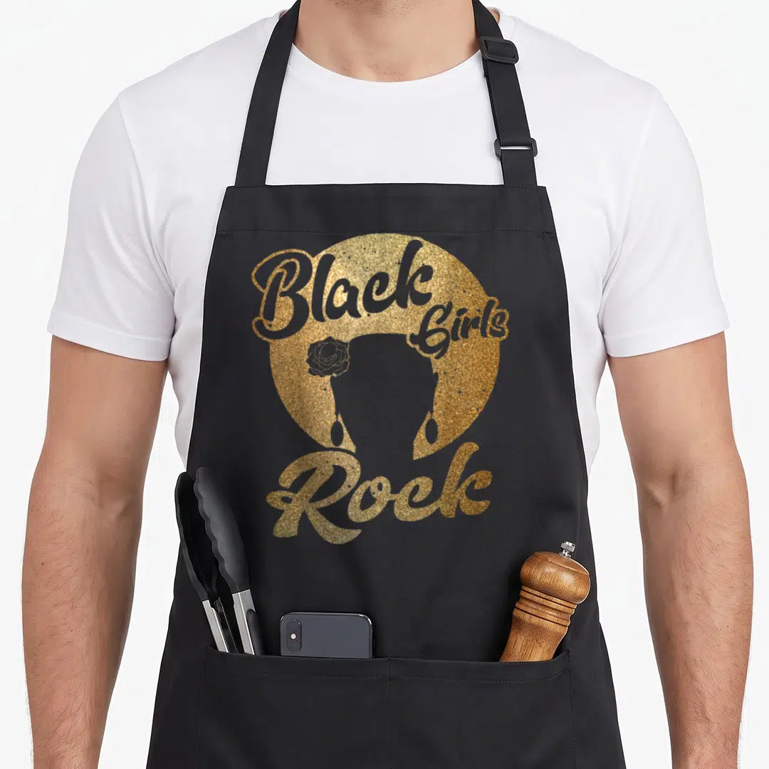 Rock strong woman apron - Gold glitter woman silhouette with flower earring and arched Black Girls Rock text — shown on a black cotton canvas apron against a white background