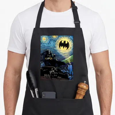 Painting nights apron - Watercolor Batman crouching on gargoyle under swirling blue yellow moon with city buildings — shown on a black cotton canvas apron against a white background