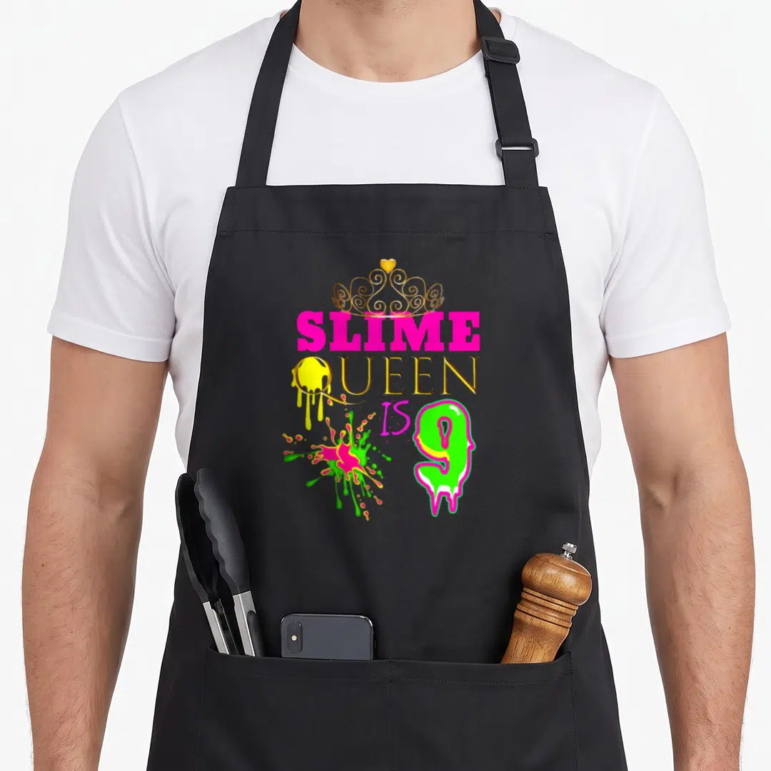 Slime queen apron - Gold crown over pink SLIME QUEEN text with green slime number 9 and yellow drip — shown on a black cotton canvas apron against a white background