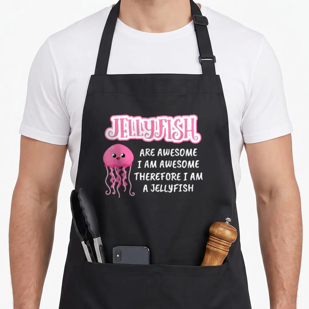 Beach jellyfish dad apron - Pink cartoon jellyfish with white text reading JELLYFISH ARE AWESOME, I AM AWESOME — shown on a black cotton canvas apron against a white background