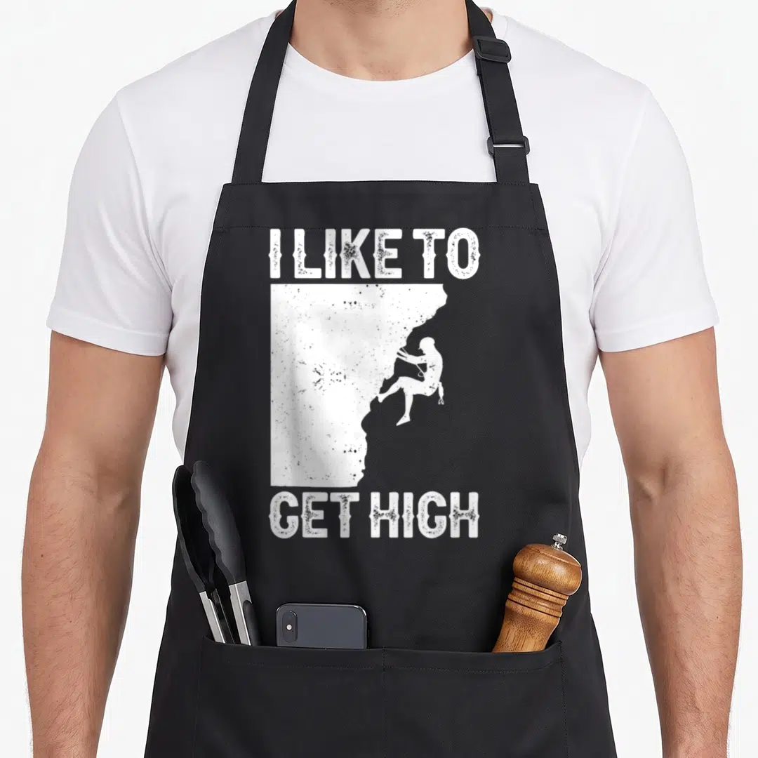 Rock bouldering apron - White distressed I LIKE TO GET HIGH text framing a rock climber silhouette on a cliff edge — shown on a black cotton canvas apron against a white background