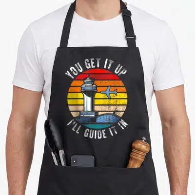 Air airplane apron - Retro air traffic control tower inside striped sunset circle with pun text — shown on a black cotton canvas apron against a white background
