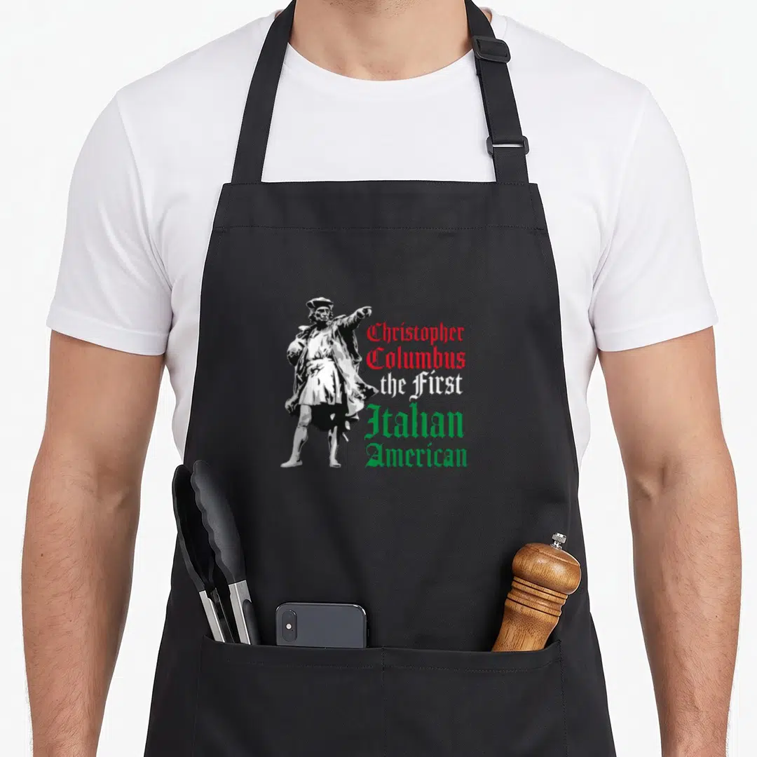 Christopher italian apron - Columbus statue pointing beside red white green text reading First Italian American — shown on a black cotton canvas apron against a white background
