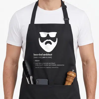 Architect beard apron - White bearded face with sunglasses and dictionary definition text — shown on a black cotton canvas apron against a white background