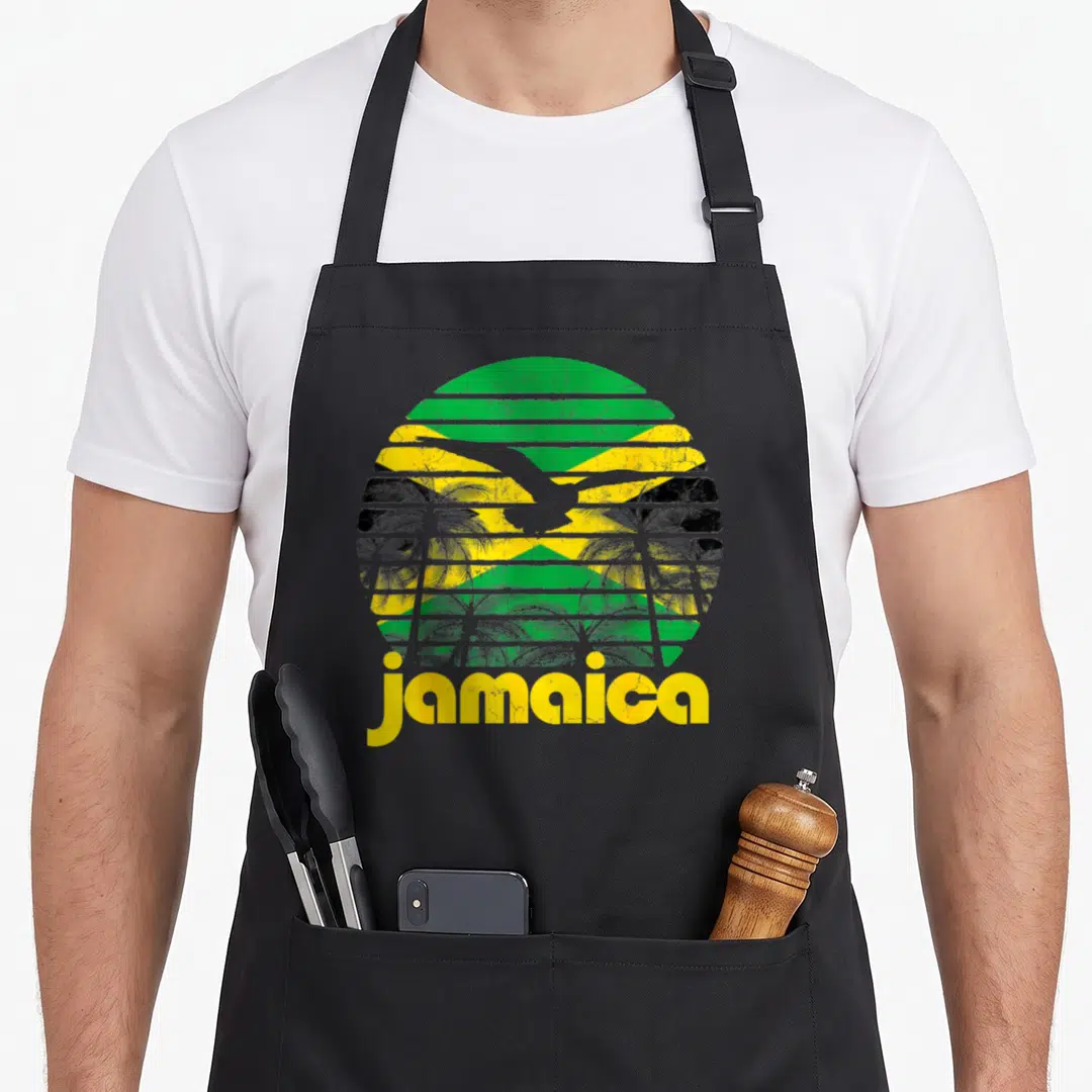 Jamaica 70s apron - Distressed circular Jamaican flag with palm trees and jamaica text in yellow — shown on a black cotton canvas apron against a white background
