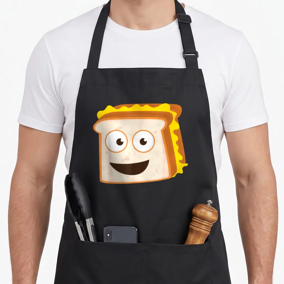 Sandwich cheese apron - Cartoon smiling grilled cheese sandwich with melting yellow cheese and brown crust — shown on a black cotton canvas apron against a white background