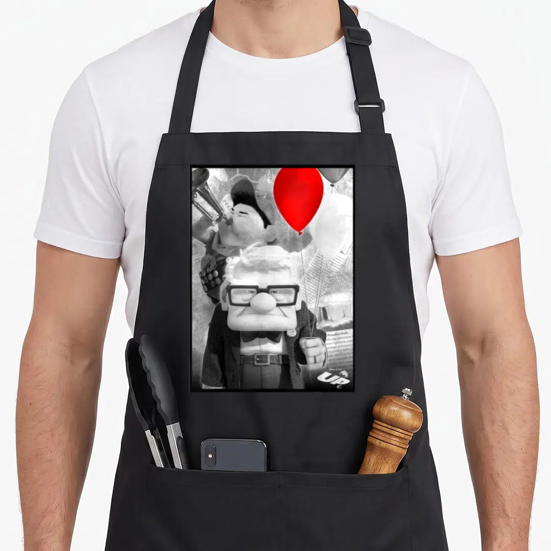 Carl trumpet apron - Carl Fredricksen holds red balloon while Russell plays trumpet behind him with UP logo — shown on a black cotton canvas apron against a white background