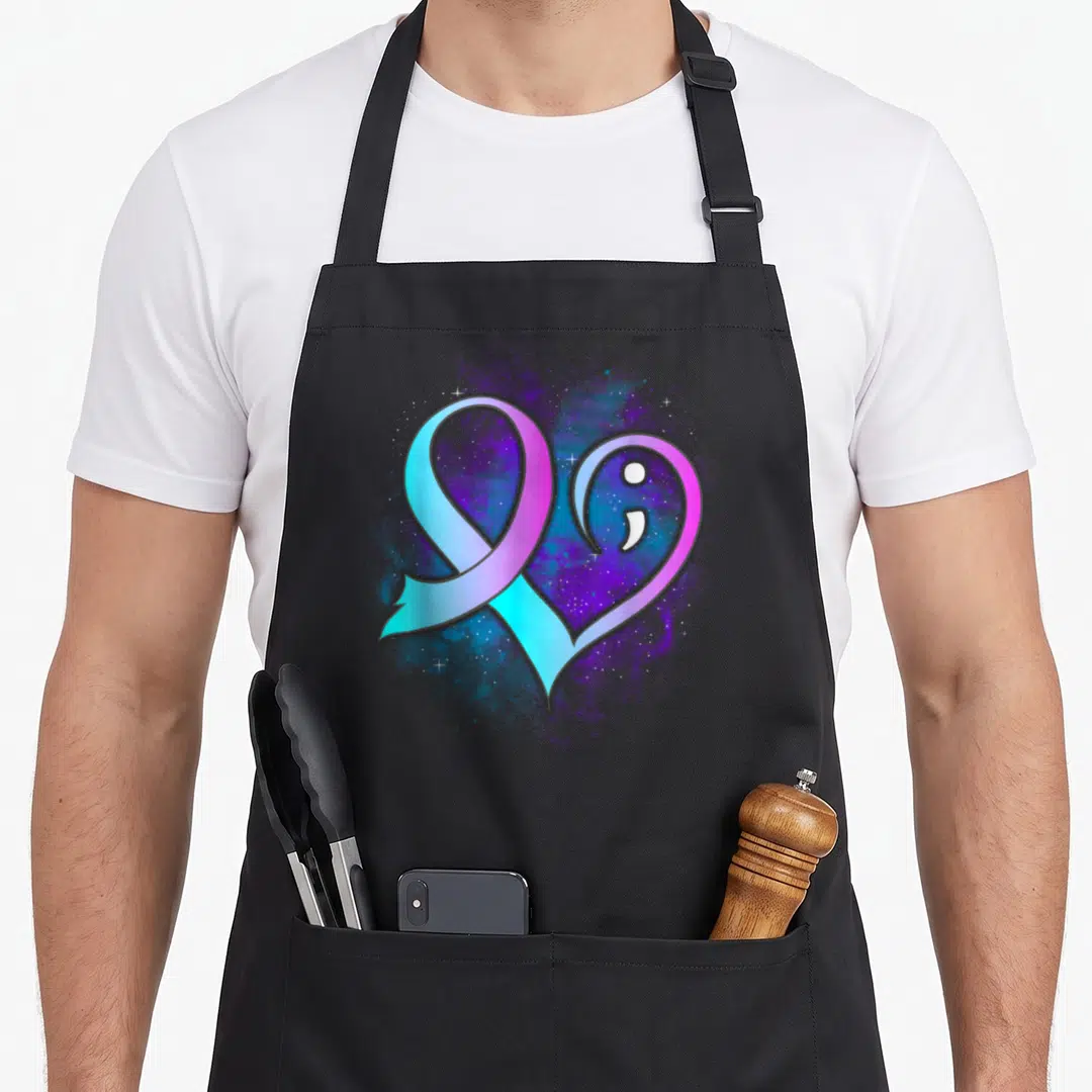 Semicolon suicide prevention apron - Gradient heart ribbon with white semicolon and stars on purple blue splatter — shown on a black cotton canvas apron against a white background