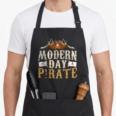Arm leg apron - Distressed pirate hat with skull, two swords, and stacked text reading Modern Day Pirate — shown on a black cotton canvas apron against a white background