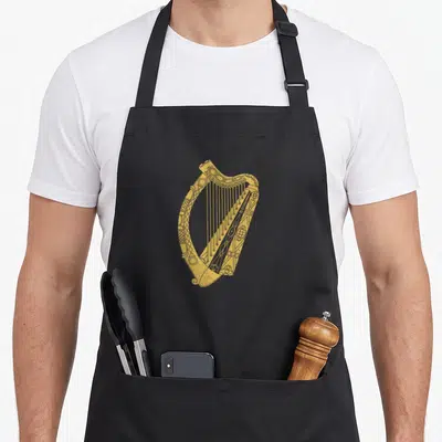 Symbol ireland apron - Gold line-art harp with Celtic details centered on grey background — shown on a black cotton canvas apron against a white background