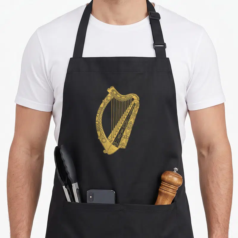 Symbol ireland apron - Gold line-art harp with Celtic details centered on grey background — shown on a black cotton canvas apron against a white background