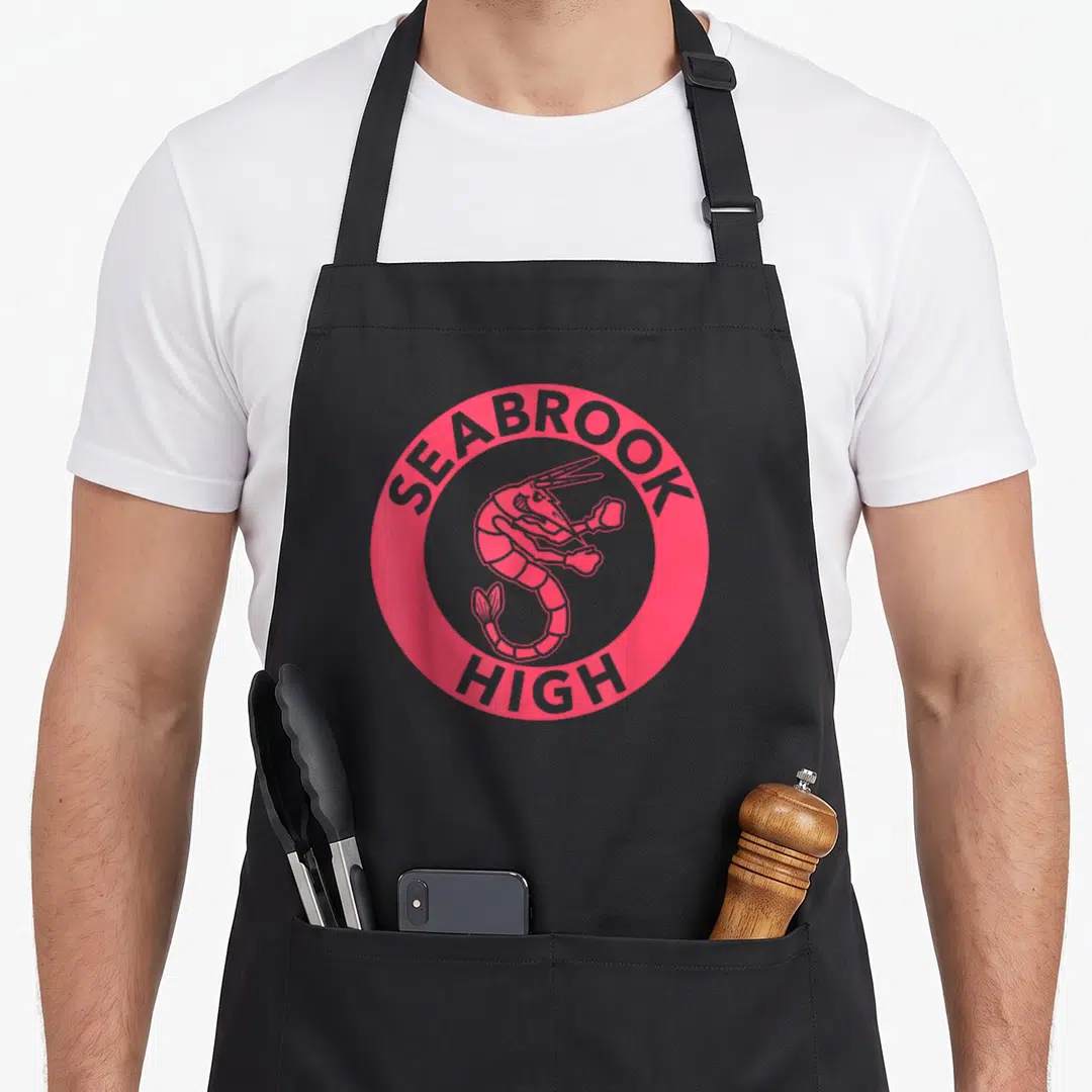 Seabrook zombie apron - Pink circle with grey shrimp and SEABROOK HIGH text — shown on a black cotton canvas apron against a white background