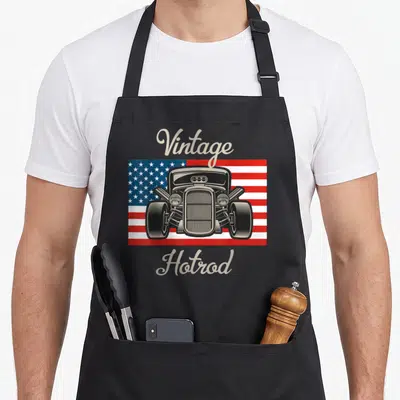 Rod antique apron - Front view hot rod car on USA flag with beige Vintage Hotrod script text — shown on a black cotton canvas apron against a white background