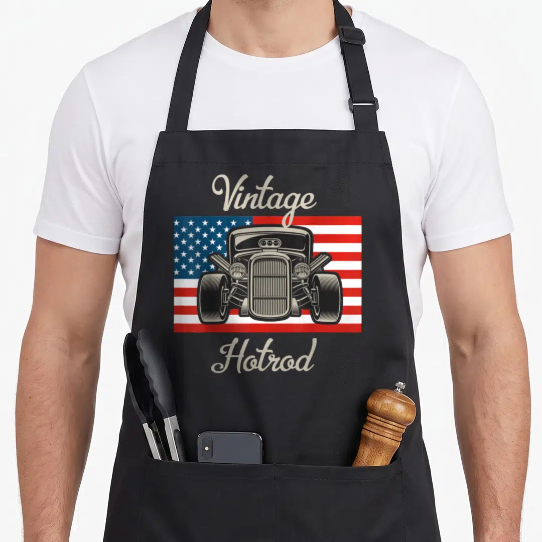 Rod antique apron - Front view hot rod car on USA flag with beige Vintage Hotrod script text — shown on a black cotton canvas apron against a white background