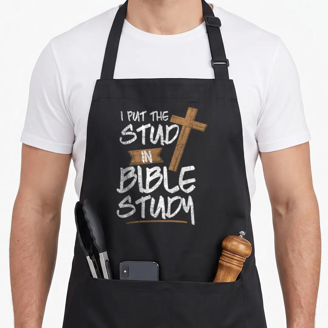 Study pastor christian apron - White stacked text I PUT THE STUD IN BIBLE STUDY with a tilted brown cross and ribbon — shown on a black cotton canvas apron against a white background