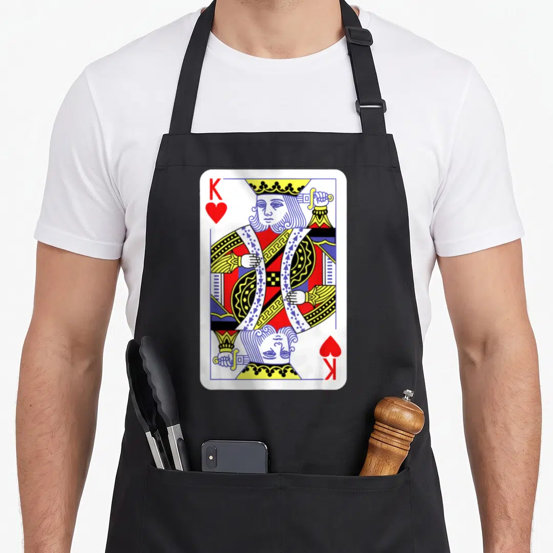 King easy apron - Mirrored King of Hearts playing card with K and heart symbols in red blue and yellow line art — shown on a black cotton canvas apron against a white background