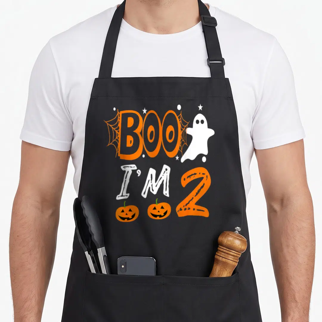 2nd funny halloween apron - Cartoon ghost and orange text reading BOO I'M 2 with two pumpkins and spider webs — shown on a black cotton canvas apron against a white background