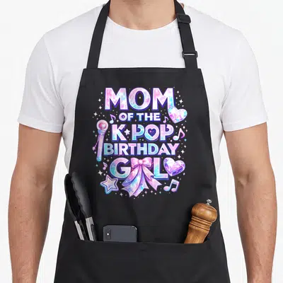 Pop birthday music korean apron - Stacked MOM OF THE K-POP BIRTHDAY GIRL text with lightstick, bow, hearts and galaxy — shown on a black cotton canvas apron against a white background