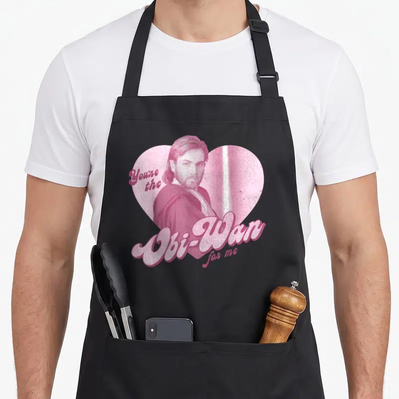 Portrait star apron - Pink heart portrait of Obi-Wan Kenobi with retro Youre the Obi-Wan for me text — shown on a black cotton canvas apron against a white background