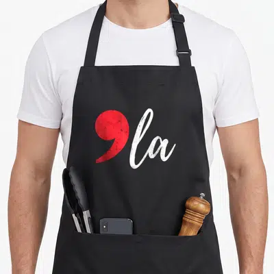 Kamala funny presidents apron - Red comma shape next to white script text reading ola — shown on a black cotton canvas apron against a white background