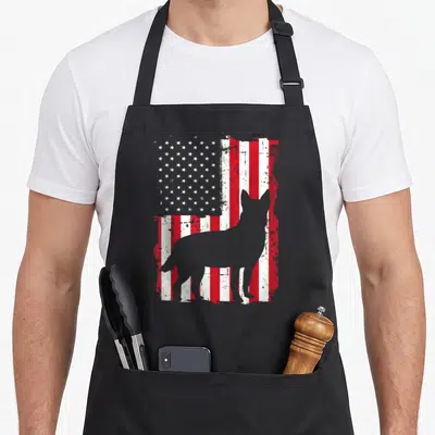 Flag dog kitchen apron - Grey dog silhouette standing in front of a distressed red white and blue American flag — shown on a black cotton canvas apron against a white background