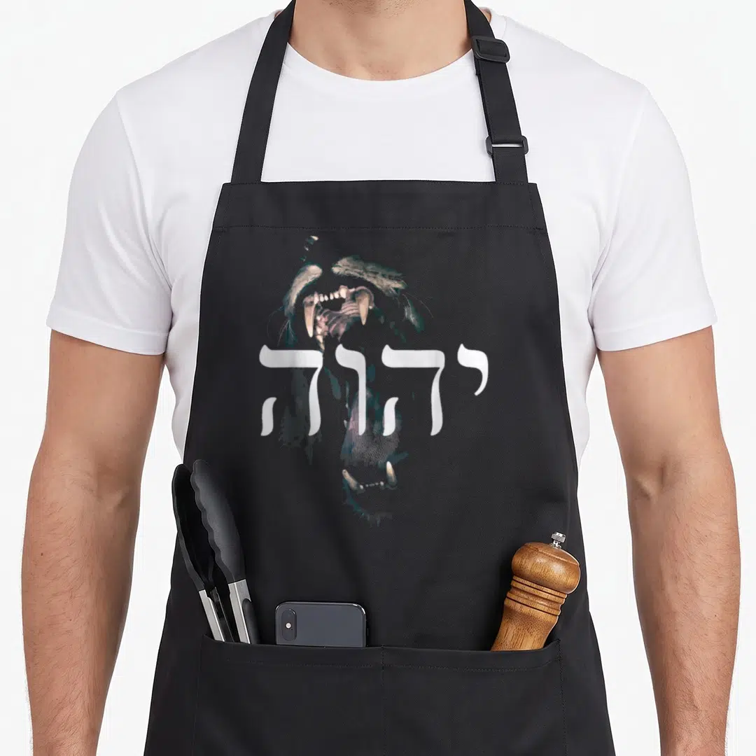 Yhwh lions apron - Distressed roaring lion head with white Hebrew text overlay on grey background — shown on a black cotton canvas apron against a white background