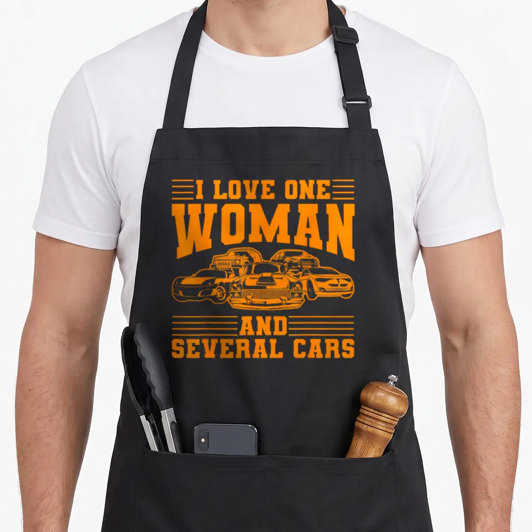 Car enthusiast auto mechanic apron - Orange distressed text I love one woman and several cars above five car outlines — shown on a black cotton canvas apron against a white background