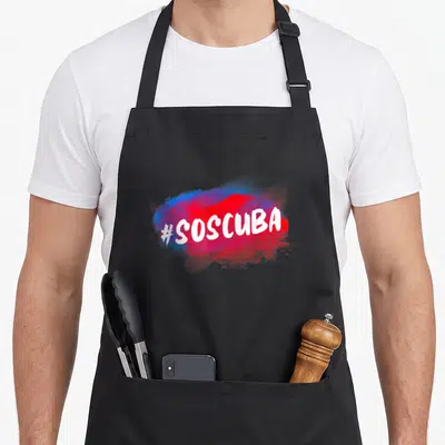 Abajo cuba libre apron - #SOSCUBA white text on red and blue paint splash graphic — shown on a black cotton canvas apron against a white background