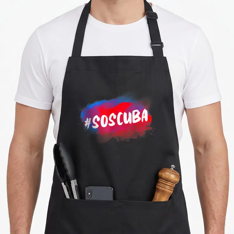 Abajo cuba libre apron - #SOSCUBA white text on red and blue paint splash graphic — shown on a black cotton canvas apron against a white background