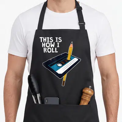 Tape 70s apron - Cassette tape with pencil and stacked text THIS IS HOW I ROLL in white and blue — shown on a black cotton canvas apron against a white background