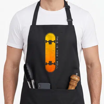 Skateboarding skateboard skateboarder apron - Yellow orange skateboard graphic with vertical white text THIS IS HOW I — shown on a black cotton canvas apron against a white background