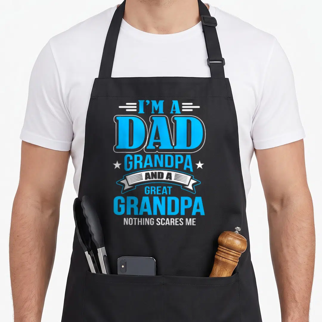 Scare grandpa apron - Stacked blue and white text reading I'M A DAD GRANDPA AND A GREAT GRANDPA NOTHING SCARES ME — shown on a black cotton canvas apron against a white background
