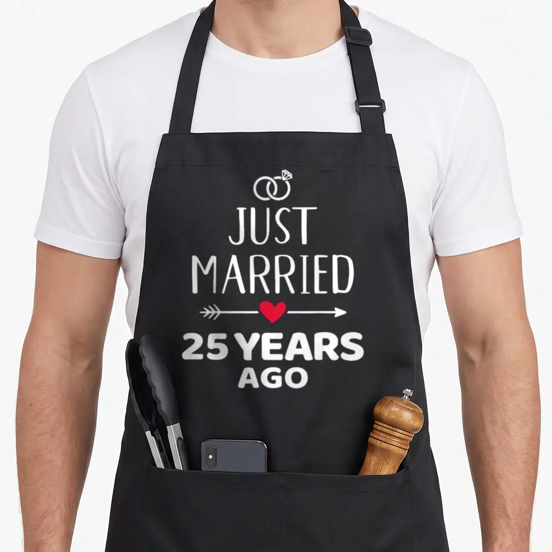 Married ago wedding apron - White rings and text Just Married 25 Years Ago with red heart arrow — shown on a black cotton canvas apron against a white background