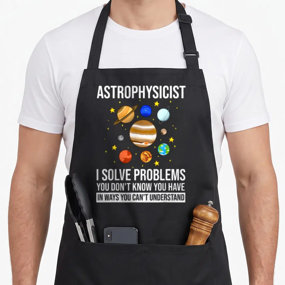 Astronomy astrophysicist apron - Cartoon planets and stars surround white text reading I solve problems you don't know — shown on a black cotton canvas apron against a white background