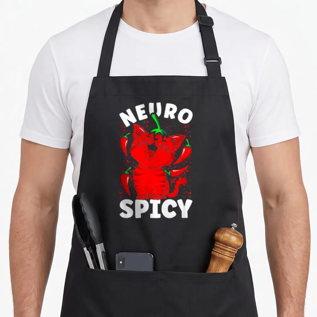 Neurodivergent cat apron - Red cartoon cat centered between NEURO and SPICY text surrounded by chili peppers — shown on a black cotton canvas apron against a white background