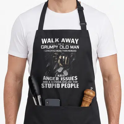 Walk dog apron - Distressed skeleton hand holding dog tags surrounded by white text on grey background — shown on a black cotton canvas apron against a white background