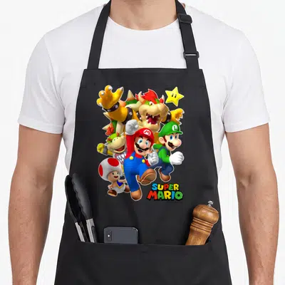 Poster shot apron - Mario and Bowser cartoon cluster with SUPER MARIO text at bottom right — shown on a black cotton canvas apron against a white background
