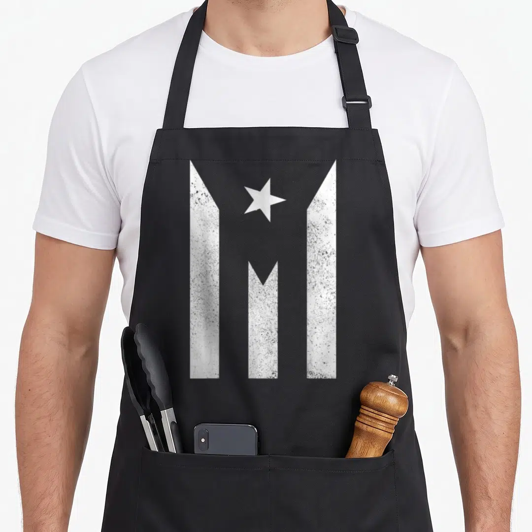 Rico flag puerto apron - Three vertical white bars with pointed tops and a centered white star in distressed style — shown on a black cotton canvas apron against a white background