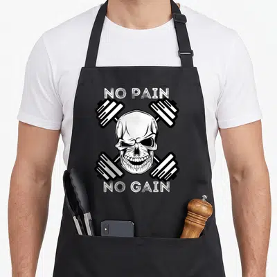 Powerlifting no pain no gain apron - White skull centered between two crossed black dumbbells with distressed text — shown on a black cotton canvas apron against a white background