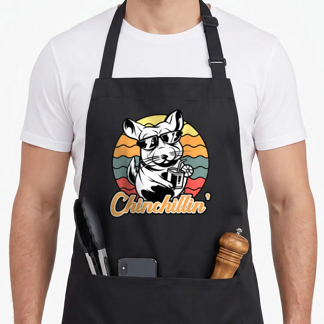 Chinchillin chinchilla dad apron - Cartoon chinchilla in sunglasses holding a drink against a retro striped sun — shown on a black cotton canvas apron against a white background