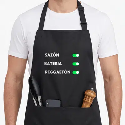 Perreo i love reggaeton apron - Three white words SAZÓN BATERIA REGGAETON next to green toggle switches turned — shown on a black cotton canvas apron against a white background