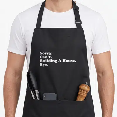 Builder construction apron - White text reading Sorry Can't Building A House Bye stacked vertically — shown on a black cotton canvas apron against a white background