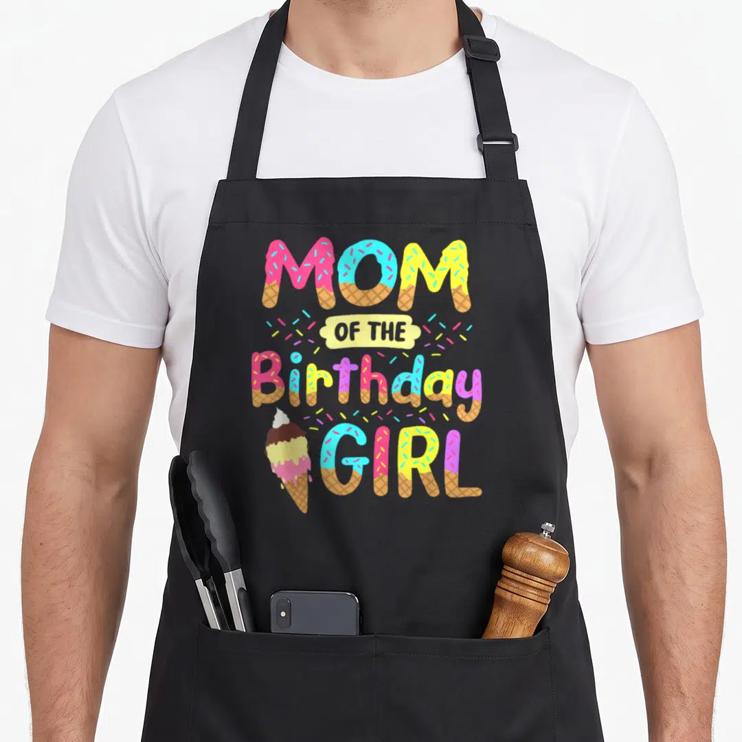 Mother ice cream apron - MOM OF THE Birthday GIRL text formed by pink blue yellow and brown ice cream cones — shown on a black cotton canvas apron against a white background