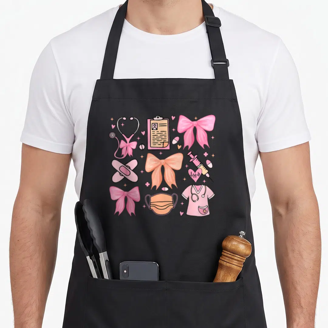 Bow nurse apron - Pink coquette bows mixed with stethoscope, scrubs, mask, syringe, and clipboard in cartoon style — shown on a black cotton canvas apron against a white background
