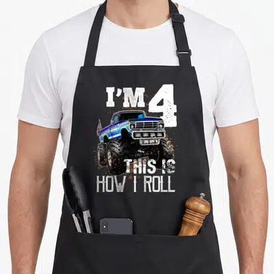 Roll monster truck apron - Blue monster truck with I'M 4 U.S.A text and mud splatters — shown on a black cotton canvas apron against a white background