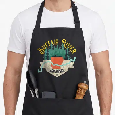River buffalo apron - Retro shield with red Arkansas map, kayaker, yellow text, and light blue river on beige ribbon — shown on a black cotton canvas apron against a white background