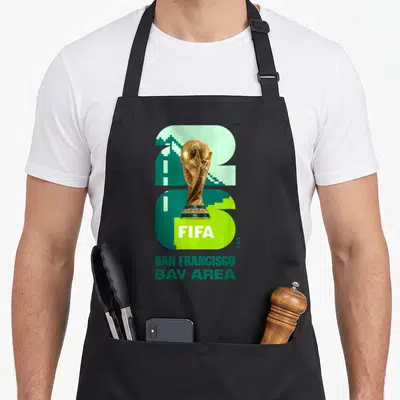 Fifa san francisco apron - Gold trophy over green 26 with San Francisco Bay Area text — shown on a black cotton canvas apron against a white background